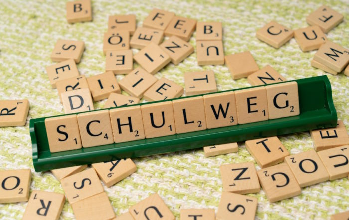 Deutsche Sprachreise - Scrabble-Steine, die das Wort „Schulweg” bilden und den Bildungsweg im Deutschlernen darstellen.