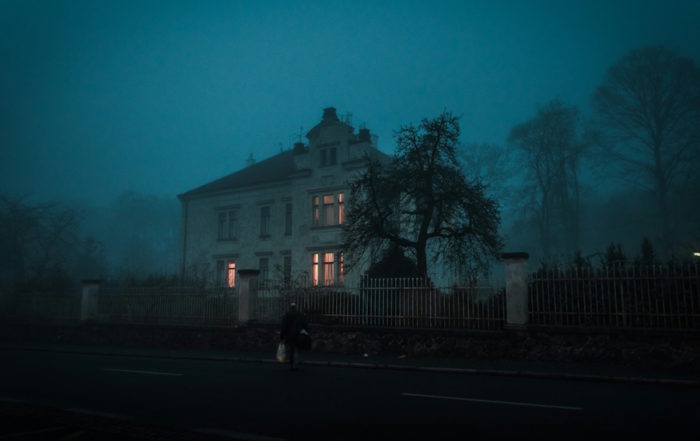 Halloween in Köln: Neblige Nachtszene mit einem Haus mit beleuchteten Fenstern und einem nahegelegenen Baum.