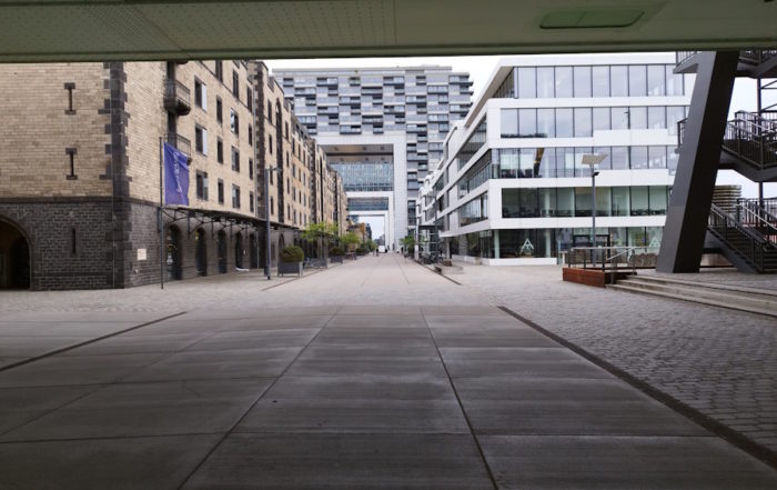 Rheinauhafen District street scene featuring a historic building alongside modern crane-shaped structures, highlighting Cologne's architectural blend.