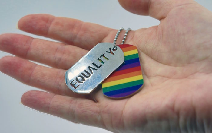 Unschuldige Liebe: Eine Hand, die Erkennungsmarken mit Regenbogenmotiv und dem Wort „Equality“ hält.