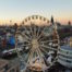 Tour-Reise in Köln: Ein lebhaftes Riesenrad steht prominent vor der Skyline der Stadt und zeigt urbanen Charme und Aufregung.