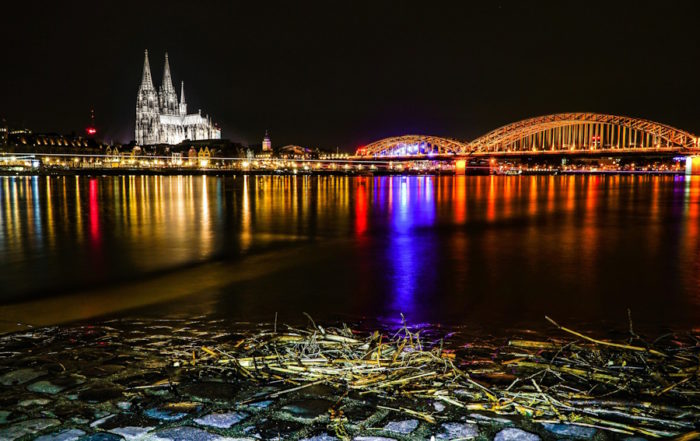 Tour trip in Cologne: A serene river flows over smooth rocks, surrounded by lush greenery and gentle water currents.