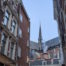 Amsterdam church tower seen between buildings.