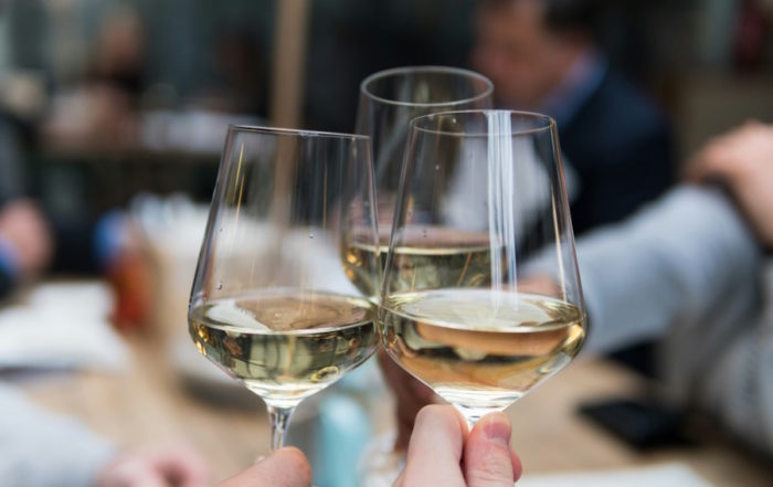 Weinfest: Eine Menschenmenge hebt bei einer Feier im Freien ein Glas Rotwein.